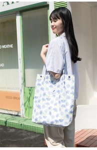 Vista de detalle del bolso tote de hombro de pana con flores casual llevado al aire libre.