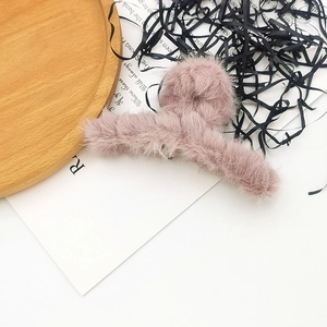 Pink plush hair claw clip for women displayed on a wooden tray with decorative accents