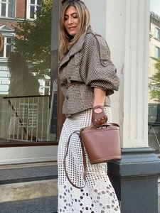 Close-up of a brown leather bucket bag styled with a vintage houndstooth wool coat