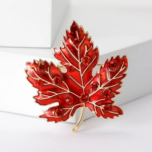 Close-up of luxury maple leaf brooch with red enamel finish and sparkling rhinestones