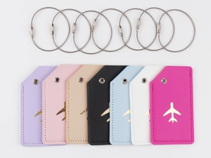 Flat lay of colorful leather luggage tags with gold airplane icons and steel loops