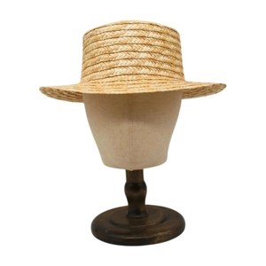 Women's summer boater straw hat with wide brim made of natural woven fibers on a display stand