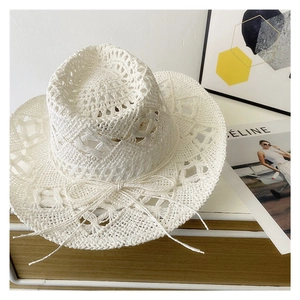 White hollow knit sun hat with bow detail presented on an elegant wooden stand