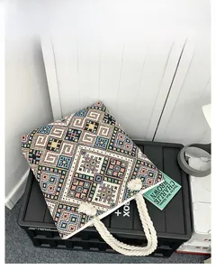 Close-up of geometric embroidery and white rope handle on ethnic canvas tote bag