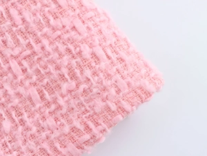 Detailansicht der rosa Tweed-Stofftextur mit aufwendigen Webfransen und Glitzer-Strasssteinen