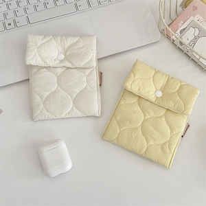 Pair of quilted storage pouches in cream and yellow on a minimalist desk