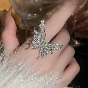 Detailed view of silver butterfly ring with cubic zirconia and pearls on finger