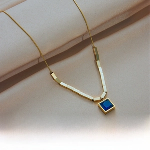 Close-up of square blue crystal pendant on a gold titanium steel chain on silk