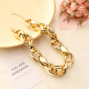 Detailed shot of chunky gold chain necklace styled on ceramic plate with pink flowers