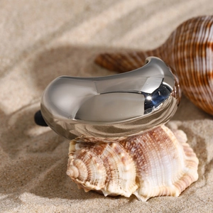 Silver bean stainless steel hair tie with a mirror polish finish on a beach setting