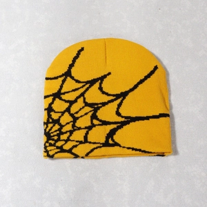 Close-up of bright yellow knitted beanie with black jacquard spider web pattern detail