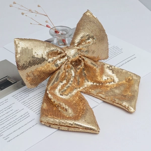 Sparkling gold sequin Christmas bow ornament placed on a vintage book for festive decor