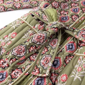 Detail of floral printed quilted cotton jacket with braided trim and waist tie strap