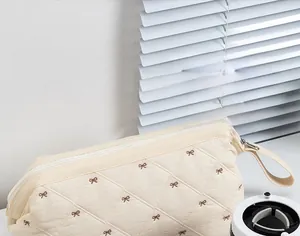 Quilted hair dryer storage bag with bow embroidery and side handle in off-white
