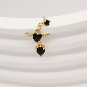 Macro shot of L-shaped nose stud featuring a black heart gem with golden wings detail