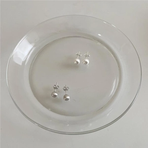 Close-up of 925 sterling silver brushed round stud earrings on a glass tray
