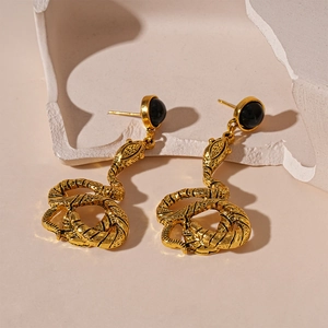 Detailed view of vintage gold snake earrings with black crystal inlay on stone