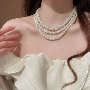 Close-up of triple-layer pearl necklace on neck showcasing elegant draped luster