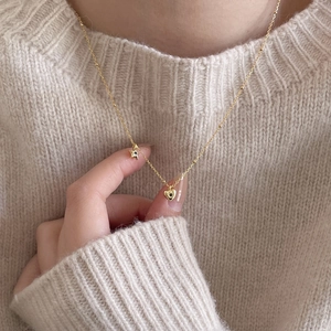 925 silver gold necklace with star and heart pendants worn on a beige knit sweater