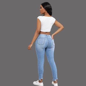 Detail view of high-waist blue skinny jeans with raw hem and white ribbed tank top