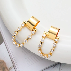 Macro shot of gold geometric earrings with white zircon inlay on white porcelain tray