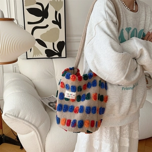 Detail of plush bucket bag featuring colorful tufted patterns and chic brand label