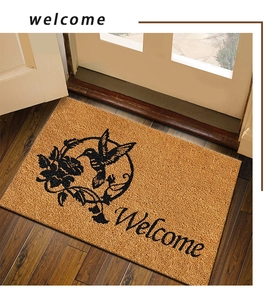 Close-up of coconut fiber doormat with hummingbird floral pattern and Welcome text