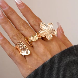 Golden irregular geometric flower ring with hammered texture worn by a model