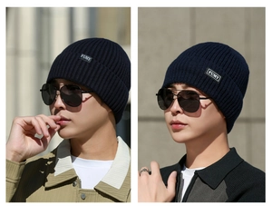 Detail view of navy blue ribbed knit beanie with white FUMY patch label and textured weave