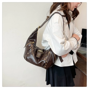 Detail der vintage braunen Halbmond-Tasche mit Goldnieten und Metallschnallen-Akzenten