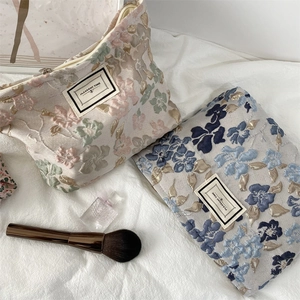 Vue détaillée du motif floral en jacquard épais sur la grande trousse de toilette