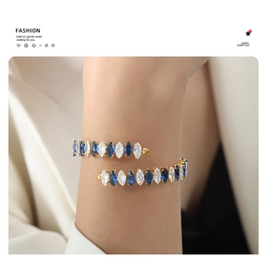 Macro detail of gold-plated wrap bracelet featuring marquise-cut blue and clear stones
