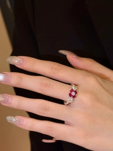 Detailed macro view of silver flower ring with red gemstone and twisted band on finger