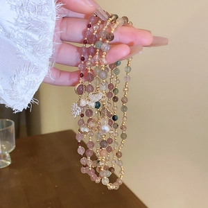 Detail of multilayer beaded bracelet with freshwater pearls and gold charms