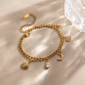 Détail d'un bracelet multicouche en acier doré 18K avec breloques lune et mauvais œil