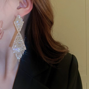 Close-up of sparkling long tassel earrings with pavé rhinestones on elegant female model
