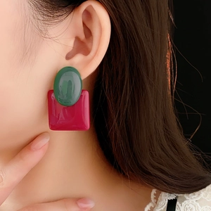 Detail shot of model wearing luxury resin earrings in dark green and rose red colors
