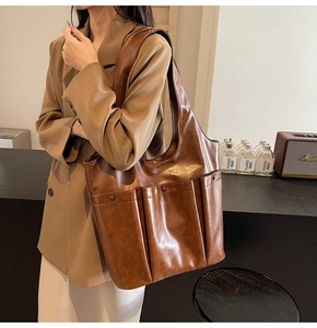 Brown PU leather tote bag with three front pockets shown in a side view on a model