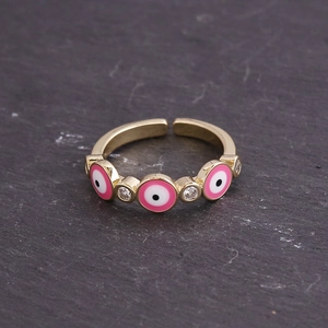 Detailed macro view of gold evil eye ring with pink enamel and sparkling zircon stones
