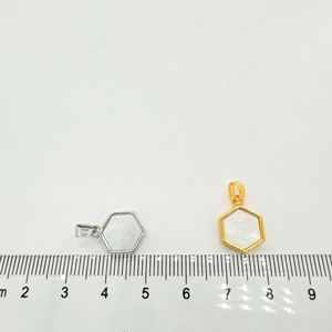Macro shot showing size of gold and silver hexagonal mother of pearl pendants next to a ruler