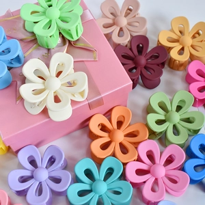 Colorful matte flower hair claws in multiple shades displayed with a pink gift box
