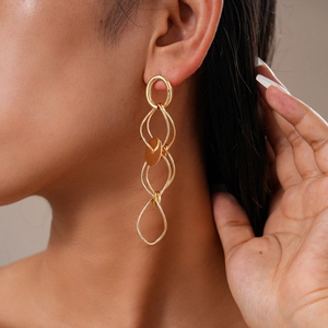 Close-up of golden layered geometric dangle earrings worn by a model in a side view