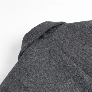 Detail of shoulder seam and thick wool texture on dark grey coat over white background
