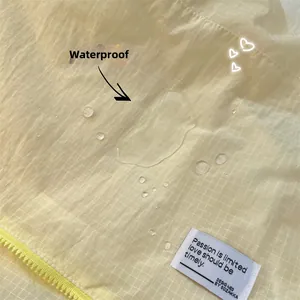 Close-up of waterproof grid fabric with water droplets and durable yellow zipper detail