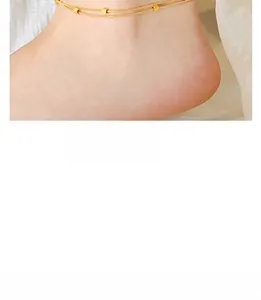 Close-up of a double-layered gold anklet with square metal beads on a model's ankle
