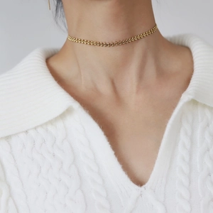 Close-up of a 18K gold plated titanium heart chain choker on a white sweater background