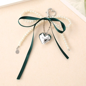 Détail d'un porte-clés à nœud en ruban vert avec perles blanches et pendentif cœur