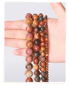 Hand holding natural Picasso stone beads in various sizes showing organic textures