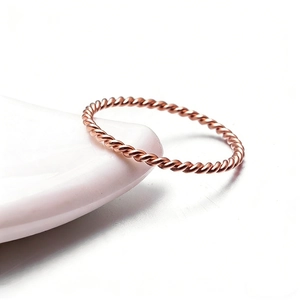 Macro shot of rose gold twisted rope ring resting on white ceramic bowl edge