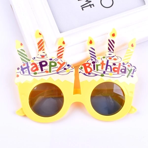 Detail of yellow birthday cake party glasses with colorful candles and Happy Birthday text